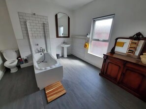 A bathroom with a bathtub, toilet, sink, and wooden vanity. - 
Authentic designer and artistic house
Family friendly
Close to Anfield and city (Liverpool)