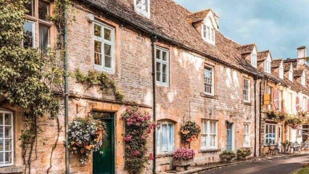 A row of stone buildings with flower boxes and a green door. - Cotswolds Country Cottage | Boutique, Romantic Retreat for Two (Purton Stoke)