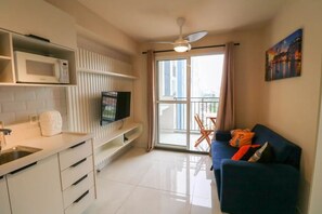 Um apartamento moderno com cozinha, sala de estar com sofá, TV e varanda com vista.