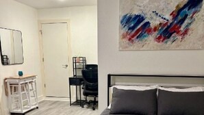 Une chambre à coucher avec un grand lit, un bureau, une chaise, un miroir et une porte.