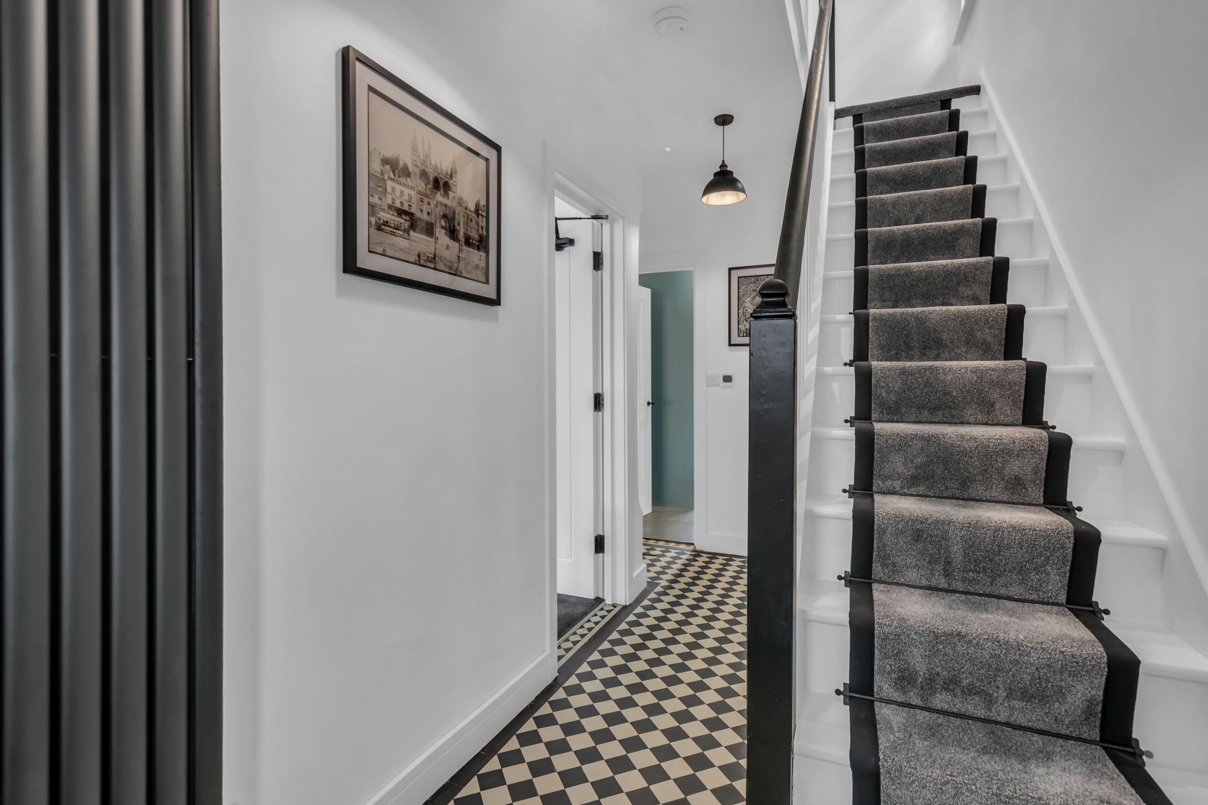 Un escalier dont les marches sont recouvertes d’un carrelage à motifs géométriques, menant à une porte.