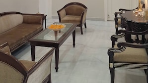 Un vaste salon doté d’un haut plafond, d’un ventilateur de plafond et d’un éclairage encastré. On y trouve deux canapés, une table basse et une table à manger avec des chaises.