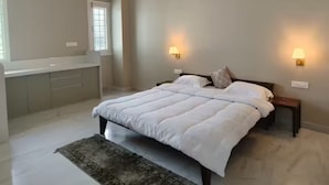 Une chambre à coucher comprenant un lit, des lampes de chevet, un ventilateur de plafond et un appareil de climatisation.
