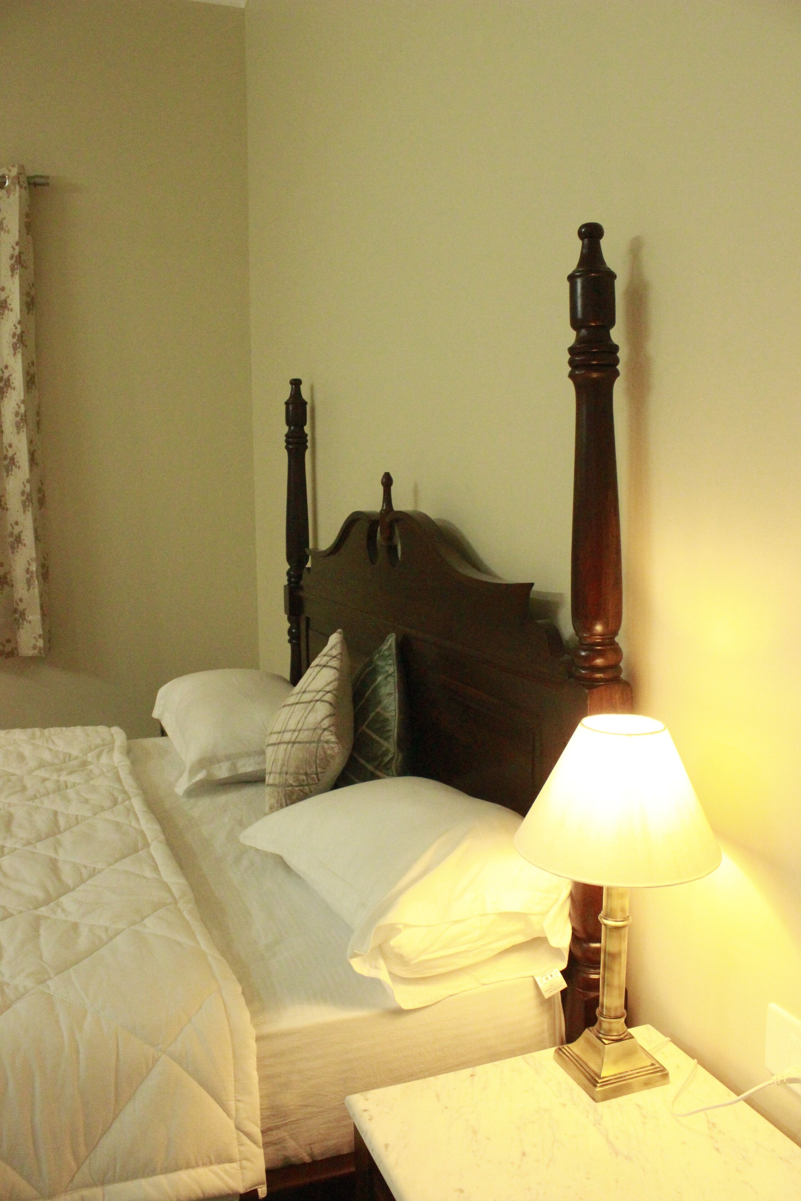 A hotel room with a bed, a nightstand, and a lamp.