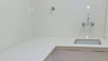 A kitchen with white cabinets, a wooden countertop, and a window above the sink.
