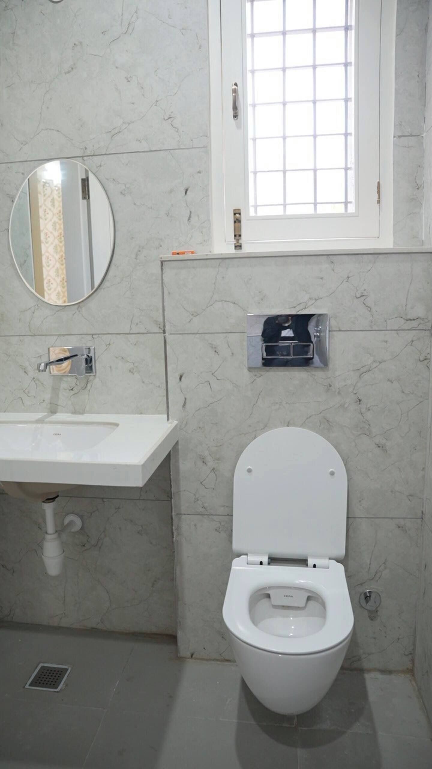 A bathroom with a white toilet, a round mirror, and a sink with a faucet.