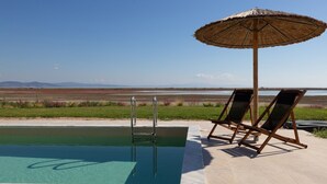 Una piscina con vistas a una playa y montañas al fondo.