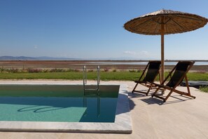 Una piscina con vista sulla spiaggia e sulle montagne sullo sfondo.