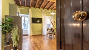 A room with wooden flooring, a dark wooden door, a dining area with a table and chairs, and a potted plant. - Giada   Charming Apartment at the Imperial Forums (ROMA)