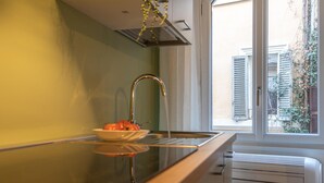 A kitchen with a modern stove, a bowl of fruit, and a window with shutters. - Giada   Charming Apartment at the Imperial Forums (ROMA)