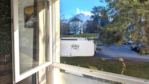 A window view of a building with a mountain in the background, a tree, and a grassy area. - Thank you Annecy - Near Lake (Annecy)