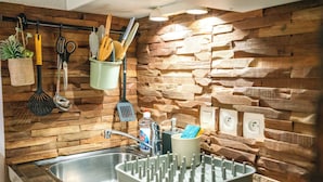 A kitchen with a stone backsplash, a sink with a dish rack, and various utensils hanging above. - Thank you Annecy - Near Lake (Annecy)