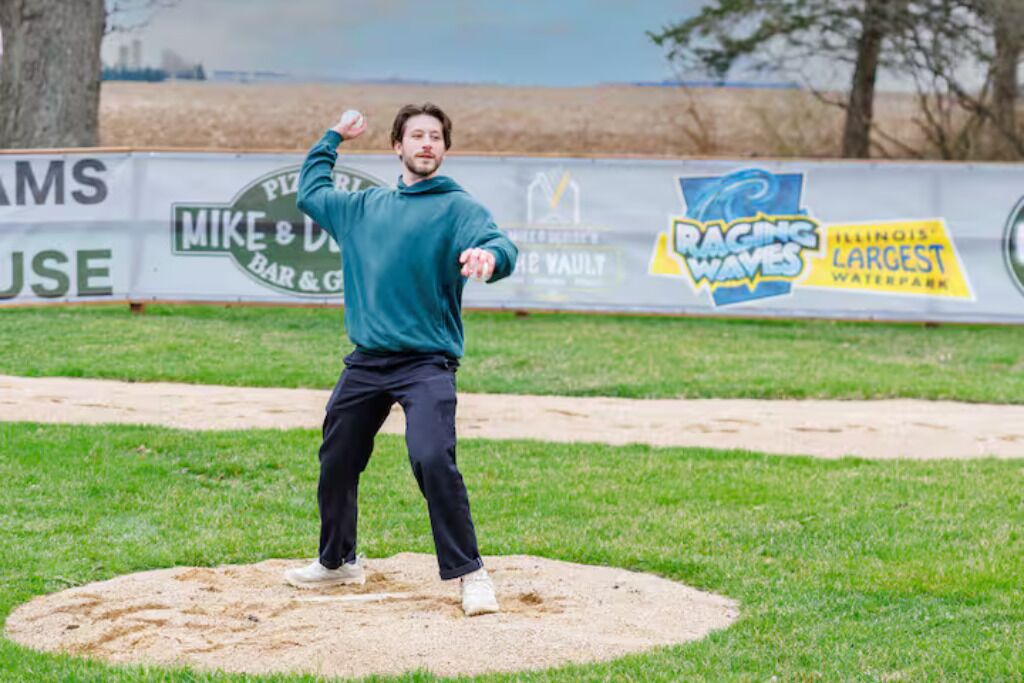 A baseball pitcher on the mound with a clear view of the surrounding area, including advertisements and a grassy field.