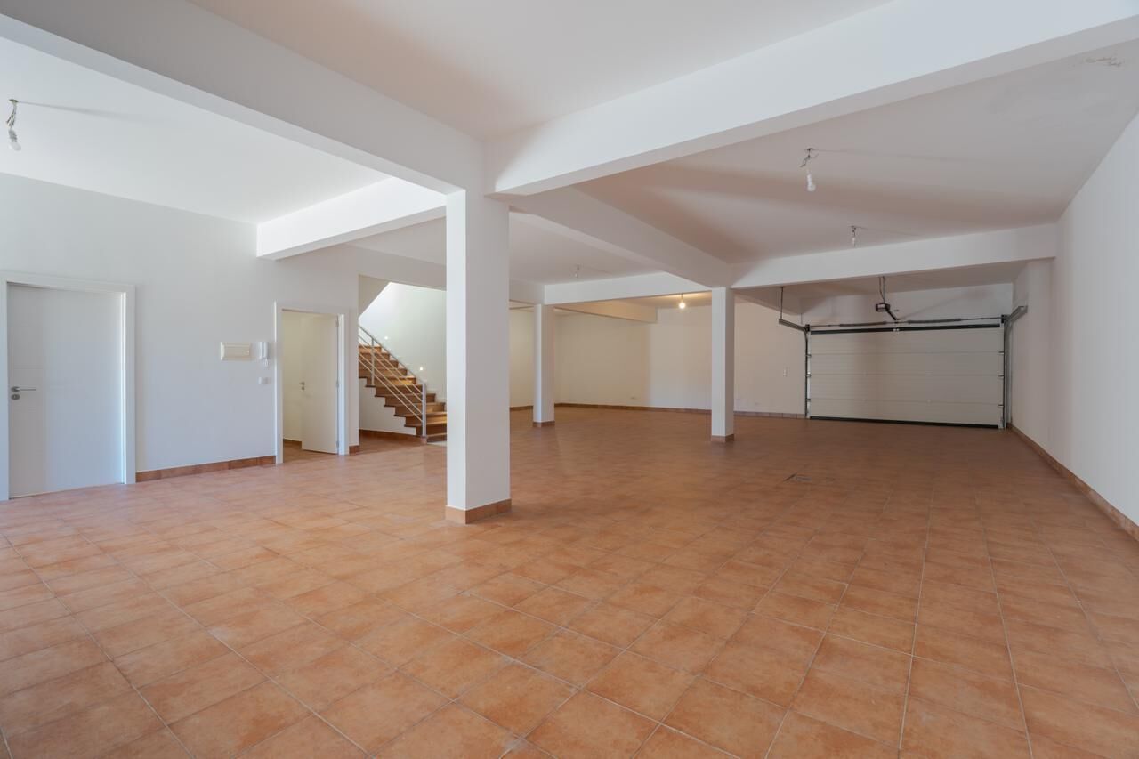 Un espacio de estar abierto con una escalera, paredes blancas y una puerta de garaje.