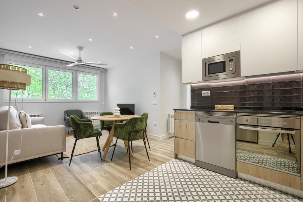 Una cocina moderna con comedor, que incluye un sofá, sillas y un ventilador de techo.