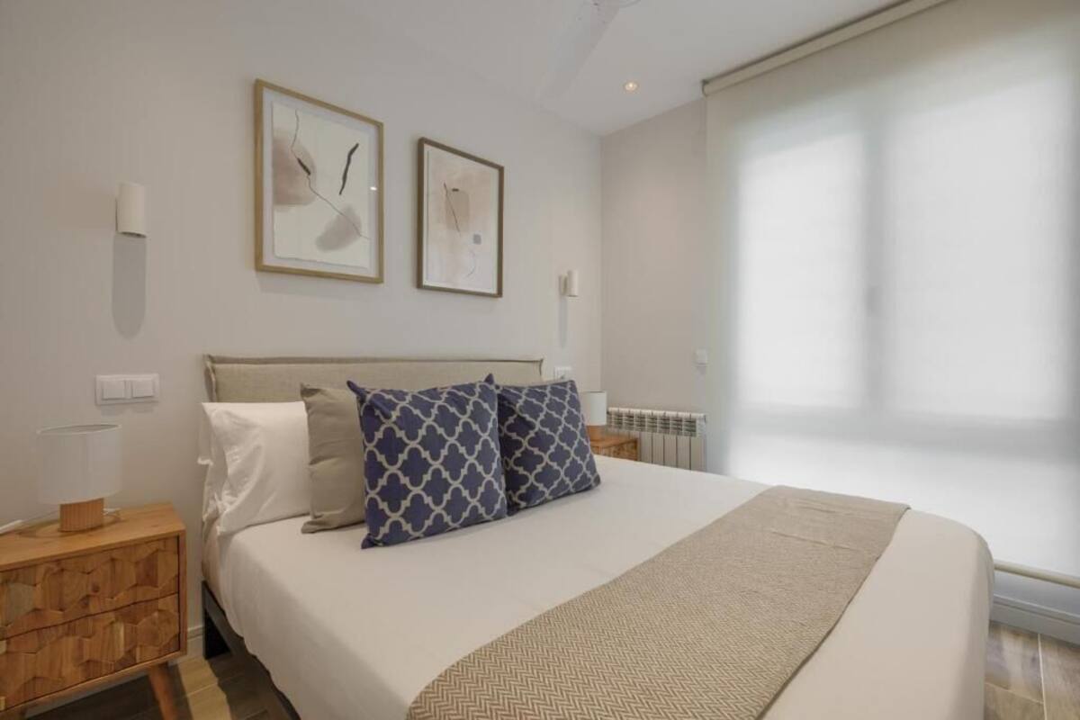 Ein modernes Schlafzimmer mit einem großen Bett, zwei an der Wand befestigten Kunstwerken, einem Holz-Nachttisch und einer Heizung.