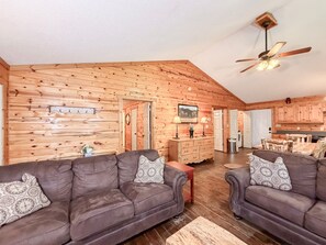 A log cabin interior with two leather sofas, a wooden dining table, and a ceiling fan. - Pet-Friendly  Mountain Cabin | Hot Tub & Fire Pit (Sautee Nacoochee)