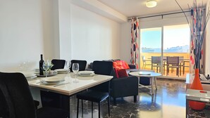 A dining area with a table set for four, chairs, a sofa, and a view of the outdoors. - Two Bedroom Apartment to rent in Carvajal (Fuengirola)
