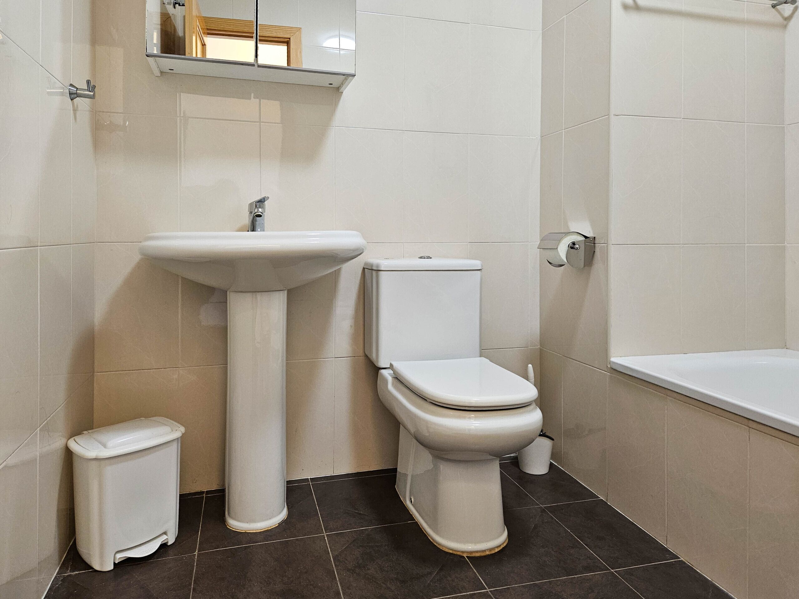 A bathroom with a pedestal sink, toilet, and bathtub.