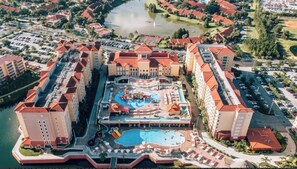 Un grande hotel con diversi edifici, una piscina centrale e una vasca d'acqua circostante.