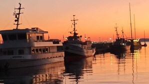 Ein Hafen im Abendrot mit mehreren vor Anker liegenden Booten.