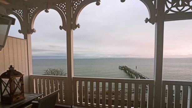 Ein überdachter Außenbereich mit Blick auf das Meer und einen Steg.