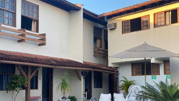 Un edificio con piscina, mobiliario de exterior y plantas en macetas.