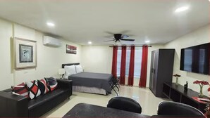 A hotel room with a bed, a sofa, a desk, a television, and a ceiling fan. - #34 Cozy in-law Port Richey Is an Entire Place (Port Richey)