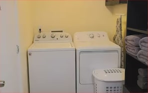 A laundry area with two white washing machines and a white laundry basket. - #34 Cozy in-law Port Richey Is an Entire Place (Port Richey)