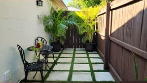 A patio with a wooden fence, a small table with chairs, and potted plants. - #34 Cozy in-law Port Richey Is an Entire Place (Port Richey)