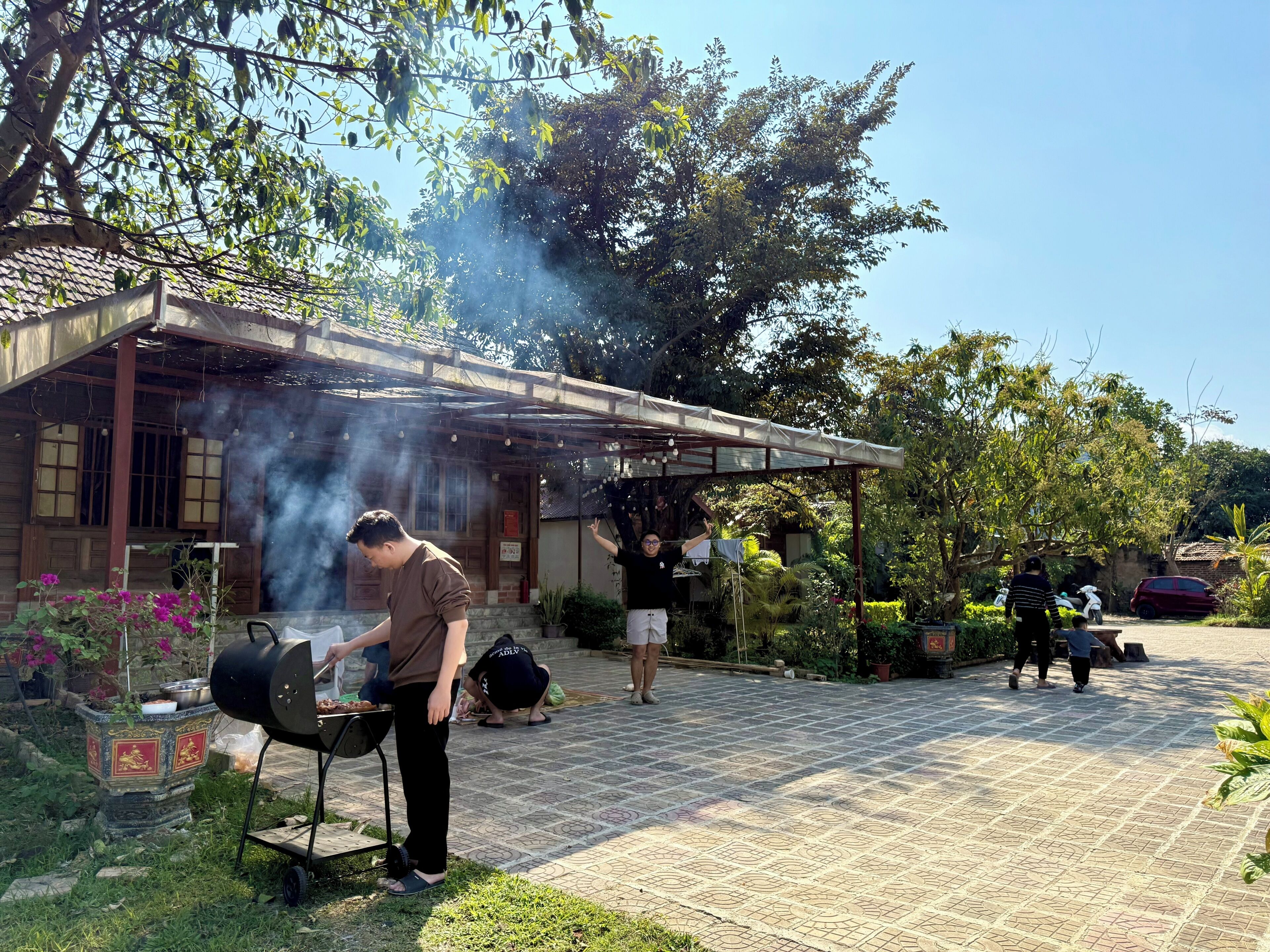 Un espace barbecue extérieur comprenant un gril, un coin salon couvert et un chemin pavé.