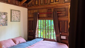Une pièce en bois avec un lit, une fenêtre avec des rideaux et un luminaire suspendu.