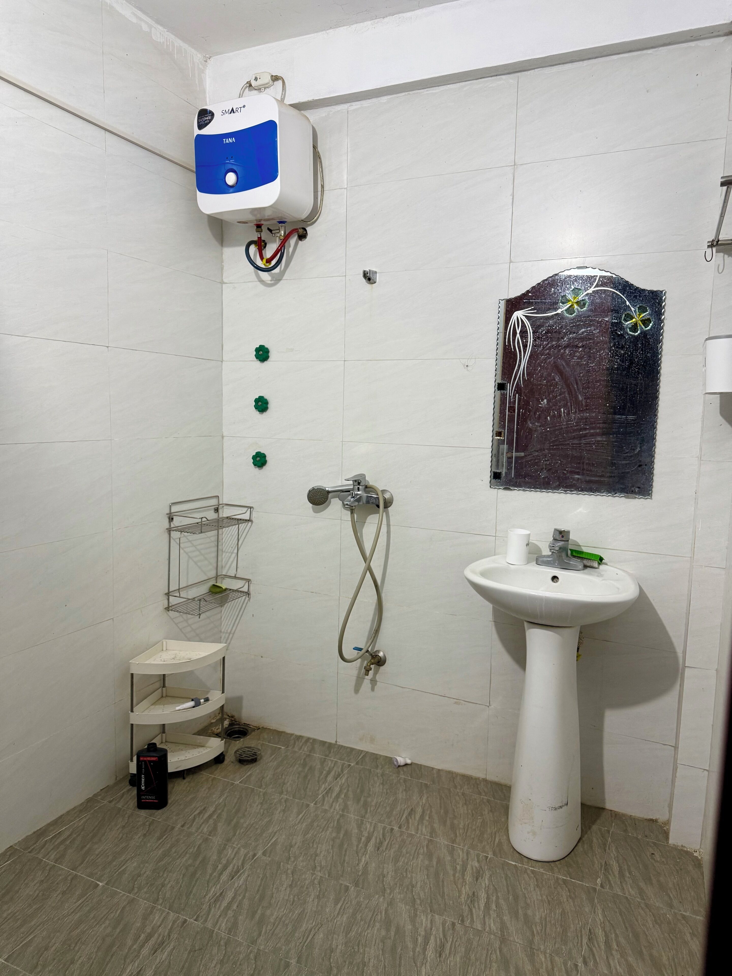 Een badkamer met een witte wasbak, een handdouche, een handdoekhouder aan de muur en een bedieningspaneel voor de douche.