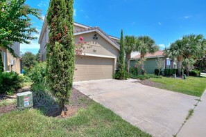 A residential house with a garage, a driveway, and a well-maintained lawn. - 25% Off 5BR Retreat! Pool/Movie Room! (Davenport)