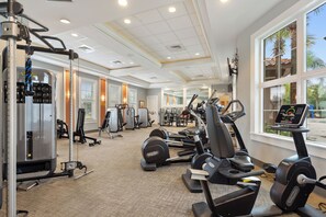 Ein Fitnessstudio mit Cardiogeräten, Krafttrainingsgeräten und einer Spiegelwand.