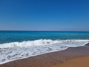 A beach with clear blue water and a sandy shore. - Self-sufficient straw bale house in organic olive grove, with sea view (Kato Samiko)