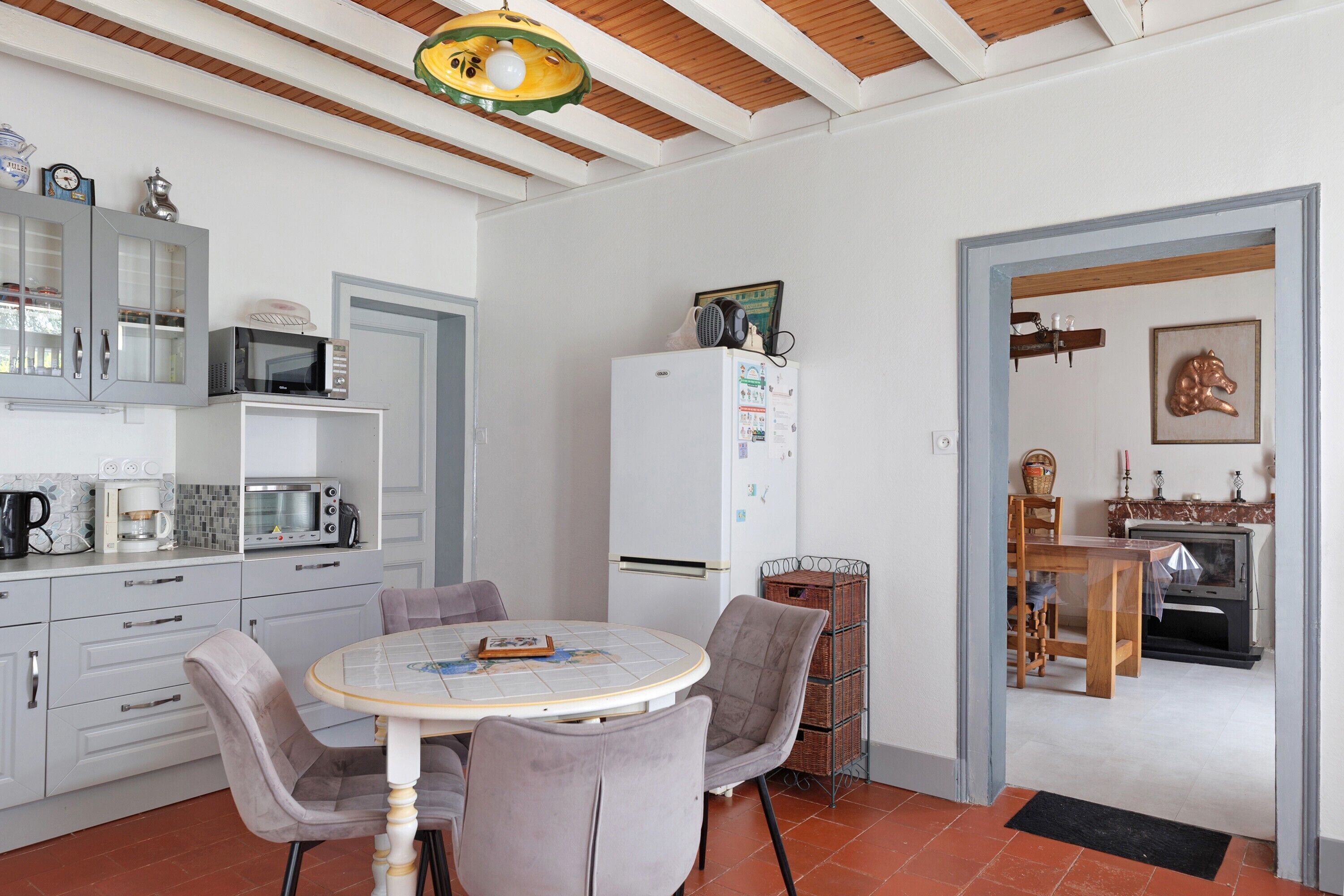 A kitchen with a dining table, chairs, a refrigerator, and a microwave.