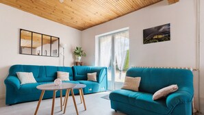 A living room with a teal sofa, a small round table, a potted plant, and a framed picture on the wall. - Gite de la Closerie – Independent Country House, Perfect for Families (Oisly)