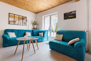 A living room with a teal sofa, a small round table, a potted plant, and a framed picture on the wall. - Gite de la Closerie – Independent Country House, Perfect for Families (Oisly)
