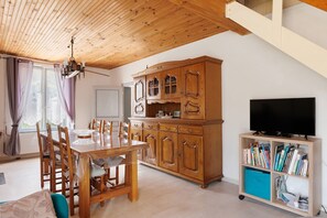 A dining area with a wooden table and chairs, a wooden cabinet, and a television on a stand. - Gite de la Closerie – Independent Country House, Perfect for Families (Oisly)
