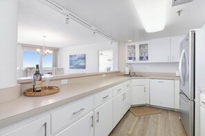 A modern kitchen with white cabinets, a stainless steel refrigerator, and a wooden countertop. - New listing! 3-bedroom. Ocean-Front, Corner Unit with Panoramic Views (Ormond Beach)