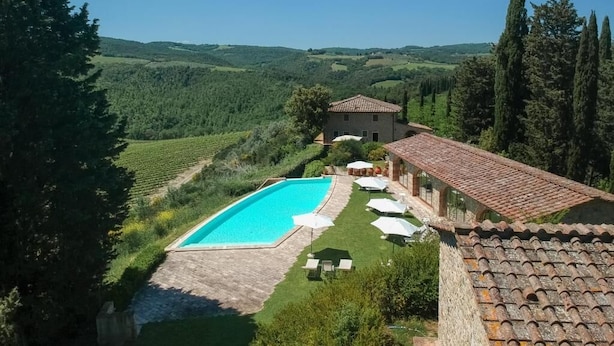 A villa with a swimming pool, outdoor seating, and vineyard views. - Santo Pietro Resort (San Gimignano)