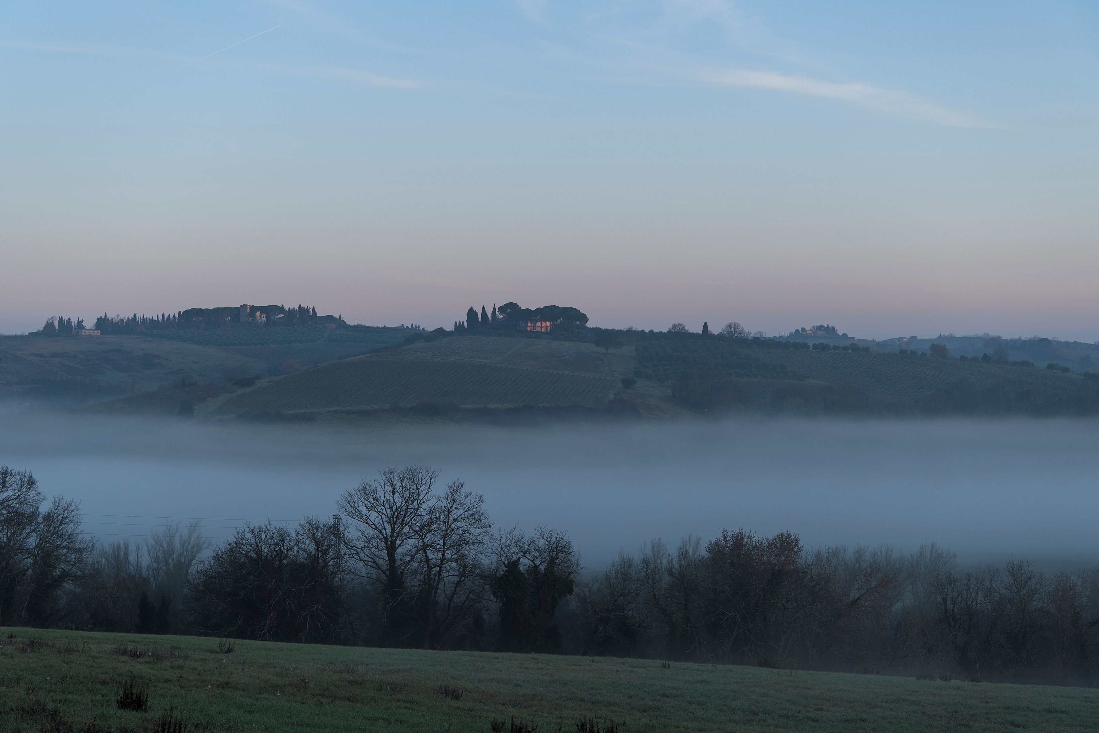 A foggy landscape with rolling hills and a distant building.