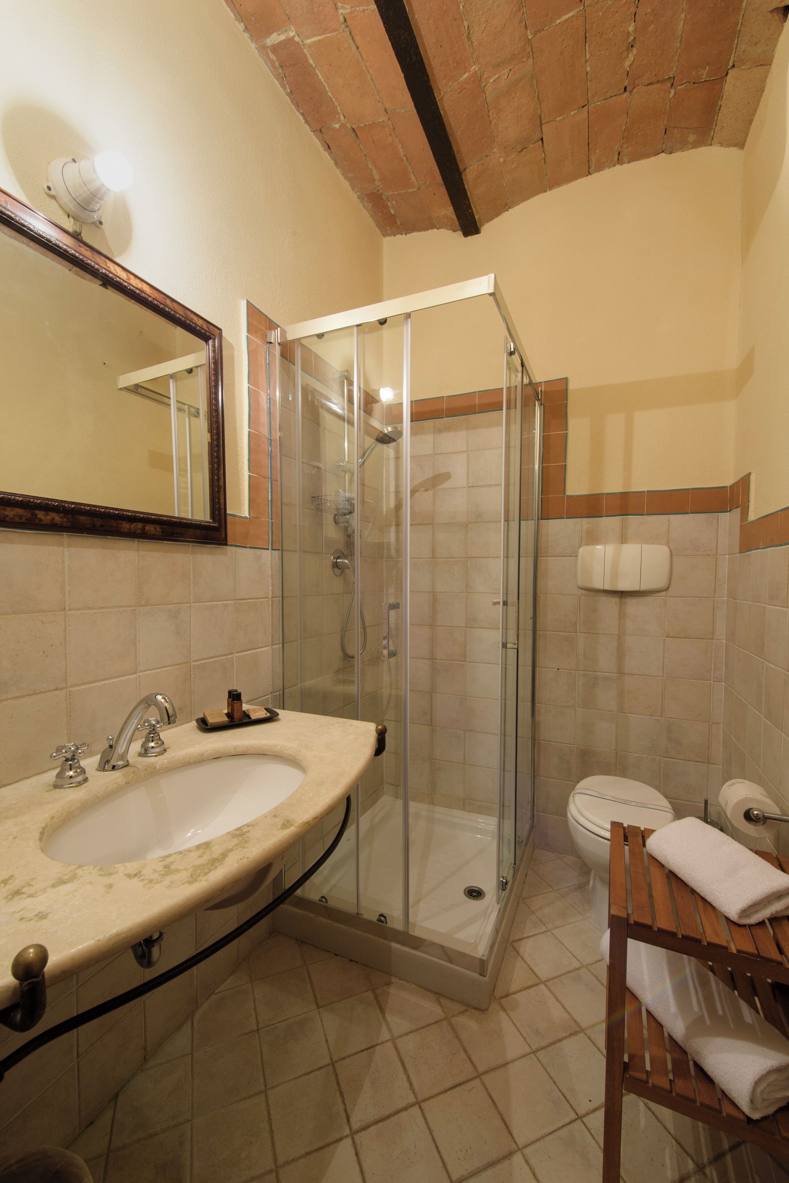 A bathroom with a sink, mirror, shower, toilet, and towel rack.