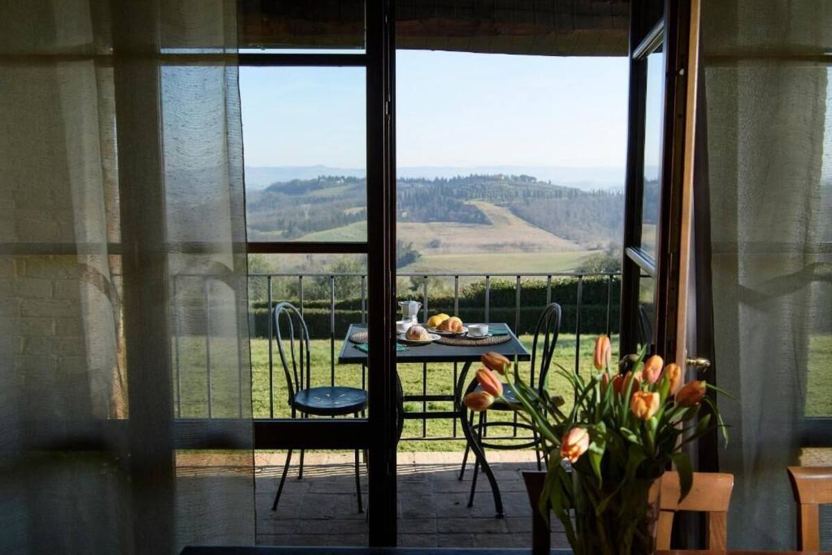 A balcony with a table set for two, chairs, and a vase of tulips.