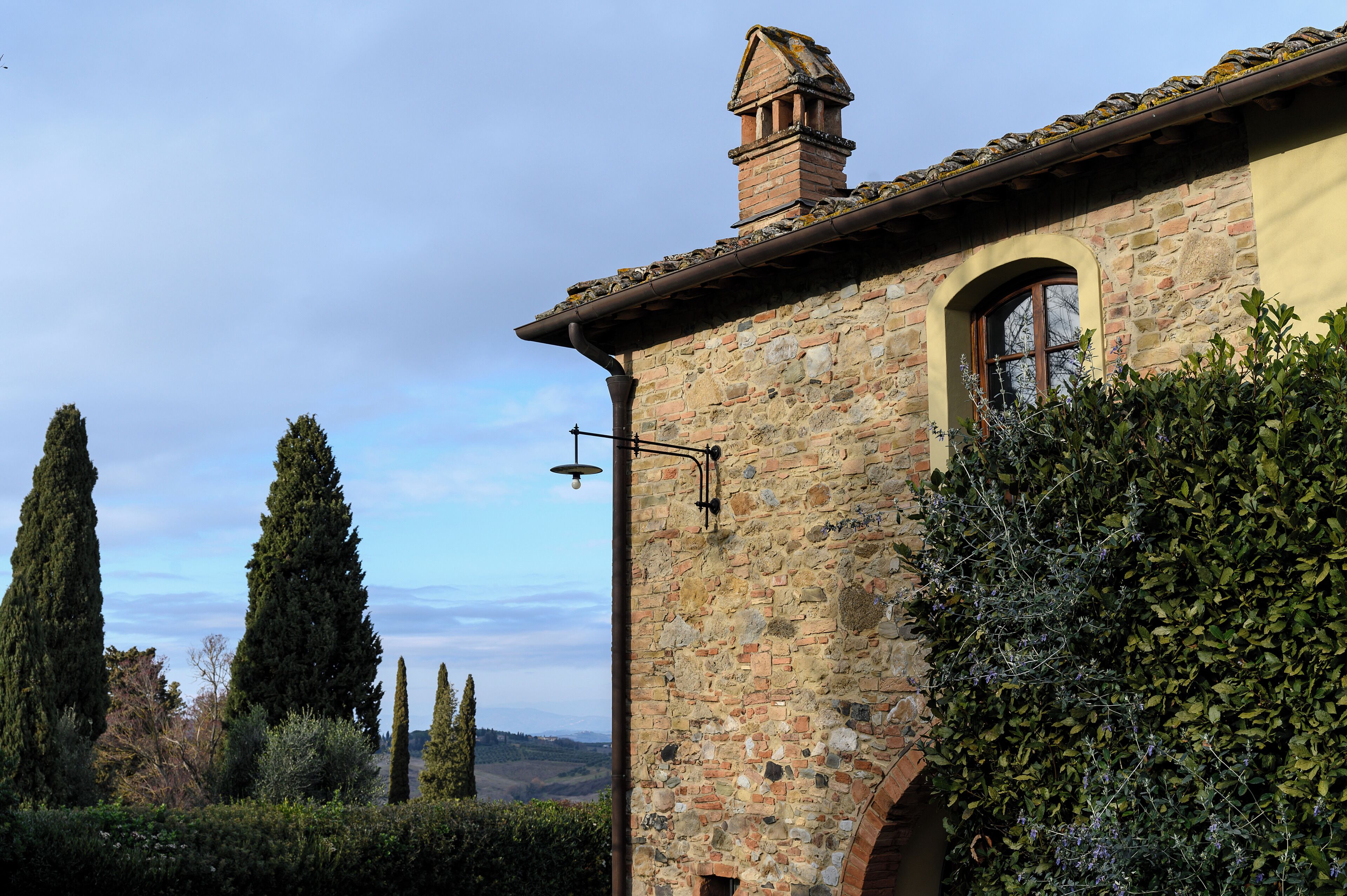 Un edificio de piedra con chimenea, una ventana y un farol.