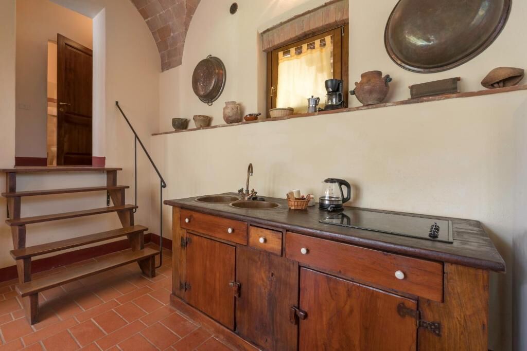 A kitchen with a wooden bench, a sink, and shelves with kitchenware.