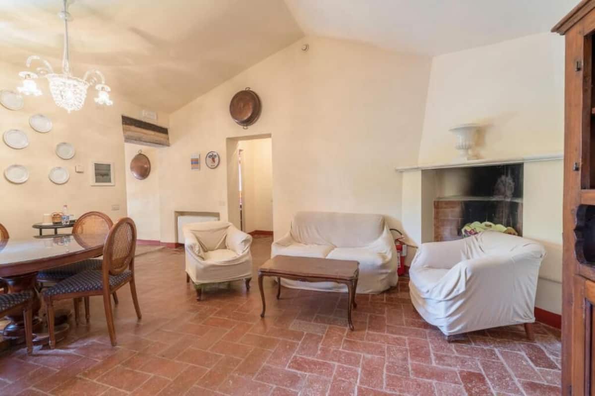 A living room with a dining table, chairs, a sofa, a fireplace, and a chandelier.