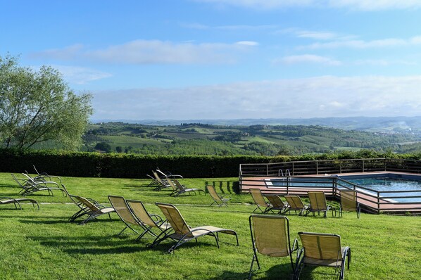 A pool area with lounge chairs and a view of rolling hills. - Santo Pietro Resort (San Gimignano)