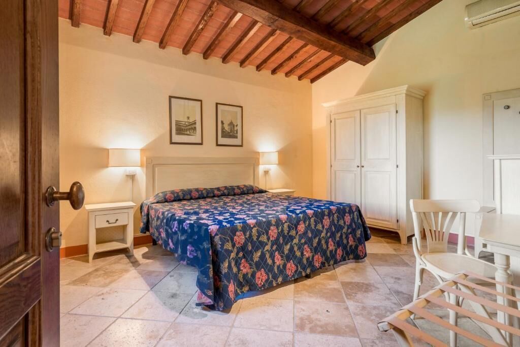 A bedroom with a bed, bedside tables, a desk, and chairs.